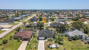 A residential area with single-family homes, a central road, and a body of water. - New Enclosed Pool, Family Friendly Oasis (Cape Coral)