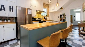 A modern kitchen with white cabinets, a central island with bar stools, stainless steel appliances, and pendant lighting. - Near Starland, River St & DT - Gaming Arcade - Large Yard (Savannah)