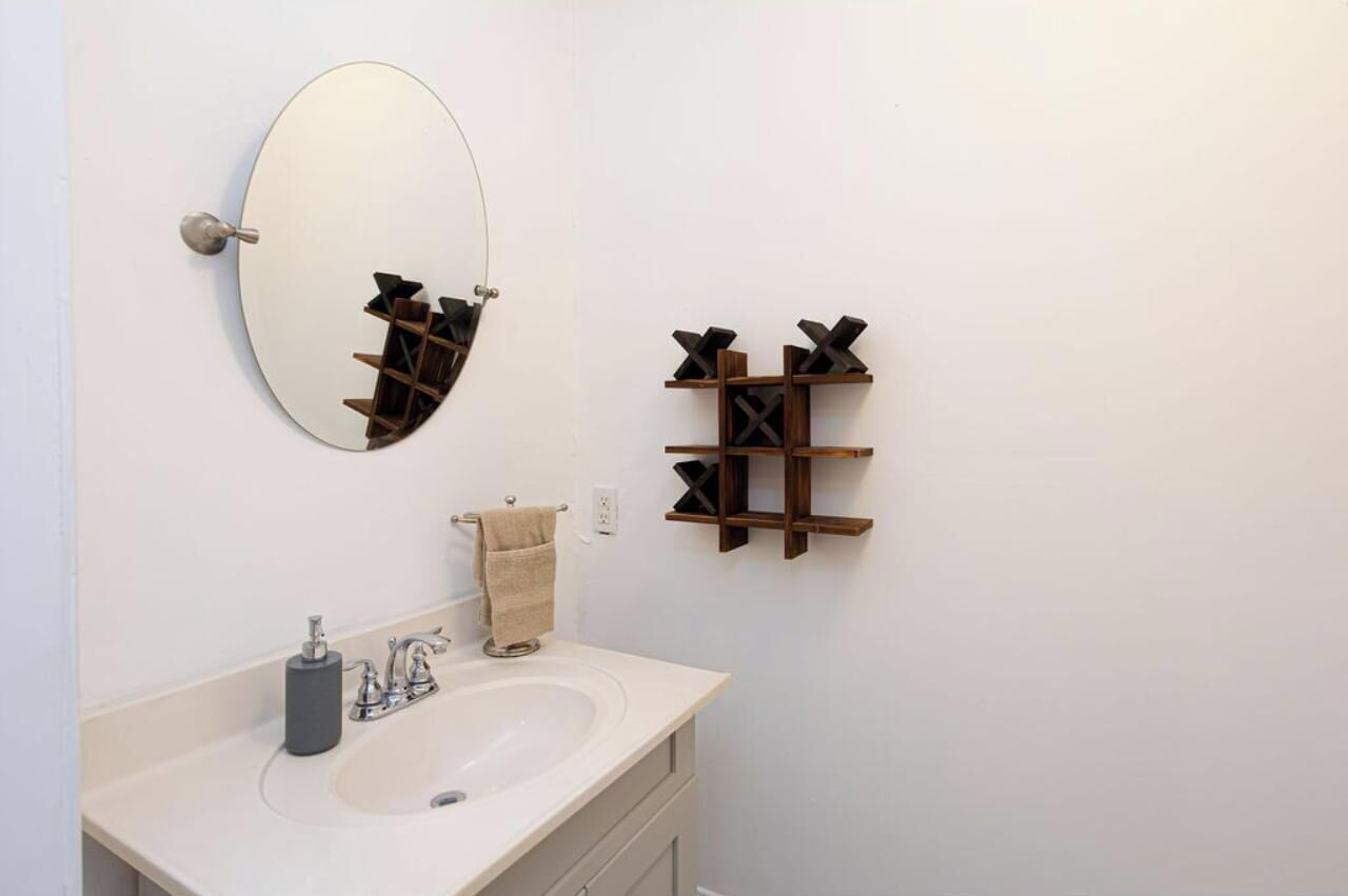 A bathroom with a sink, mirror, towel rack, and a wooden shelf unit.