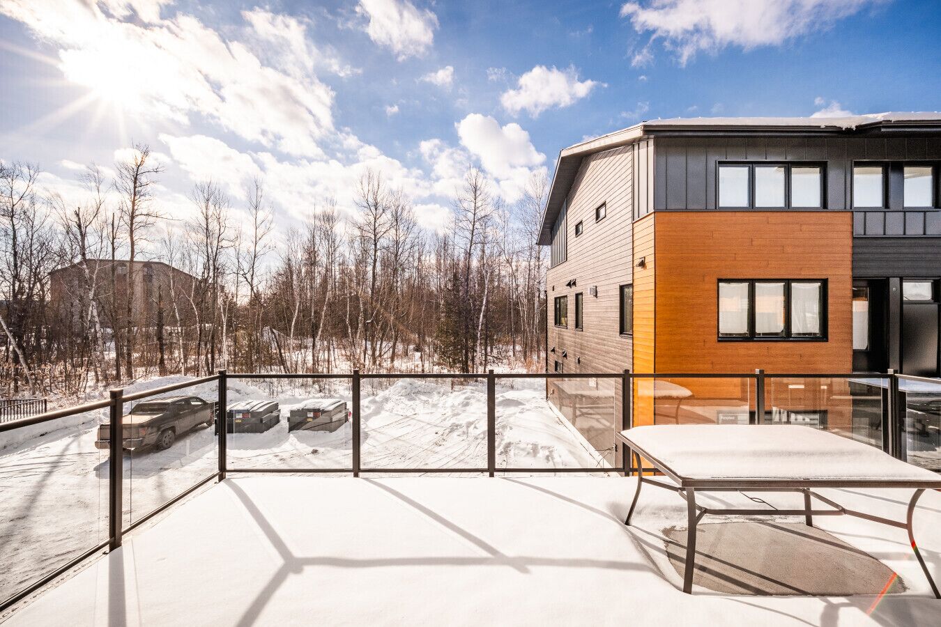 A modern building with a balcony, a snow-covered ground, and a clear sky.