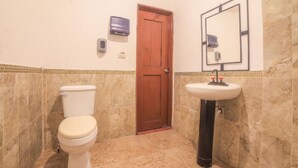 A bathroom with a toilet, sink, and a wooden door. - Centro de Aventuras Tatu (San Miguel de Allende)