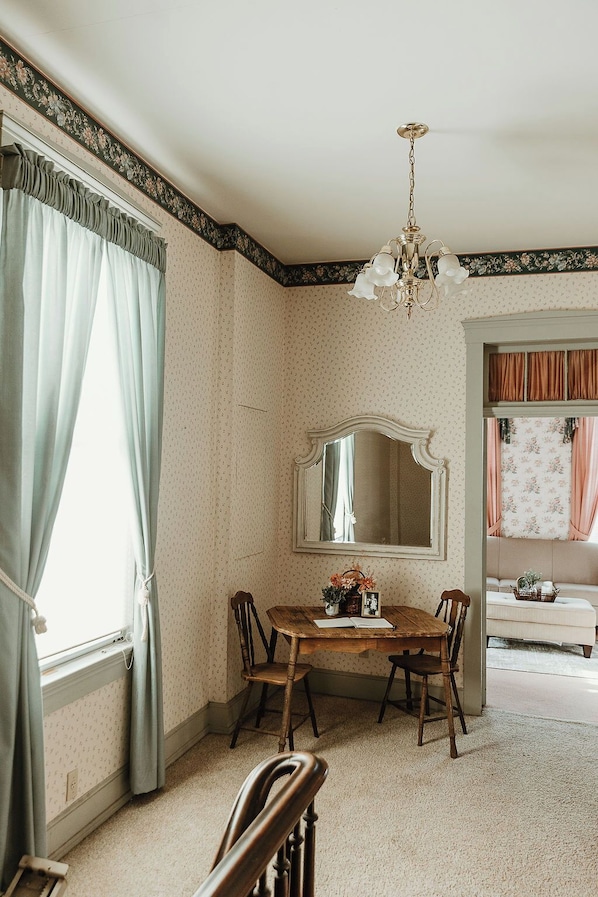 A dining room with a wooden table, chairs, a chandelier, and a large mirror.