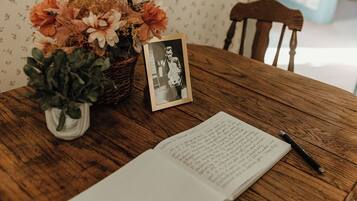 A wooden table with a book, a pen, a framed photo, and a vase with flowers.
