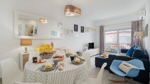 A modern living room with a dining area, a sofa, and a TV.