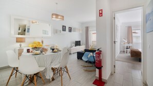 A modern living room with a dining area, a sofa, a TV, and a fire extinguisher.