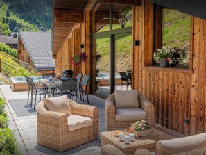 Une maison avec une façade en bois, une terrasse, un espace salon extérieur et un jacuzzi.