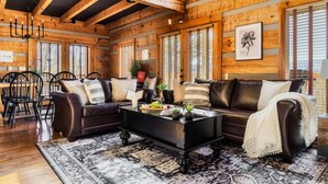 A wooden interior with a sofa, coffee table, and dining area.