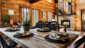 A wooden dining room with a fireplace, black chairs, and a table set for four.