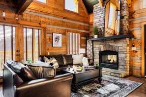 A log cabin interior with a stone fireplace, leather sofa, and large windows. - Million$View,New,Hot Tub,Pool Table,Game (Seviervill)