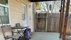 Una terraza de madera con una mesa, sillas, un tapete y una maleta.