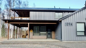 A two-story building with a metal exterior, a wooden deck, and a number '1394' on the side.