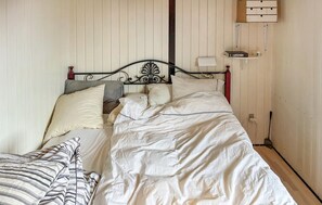 A bed with a metal headboard, a bedside table, and a shelf with a book and a small object.