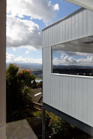A modern building with a large window offering a view of a cityscape and mountains. - Serene Trevallyn Escape & Views (Trevallyn)