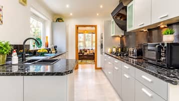 Een moderne keuken met een centraal eiland, ingebouwde apparatuur en uitzicht op de eetruimte.