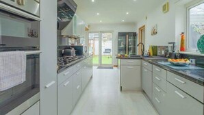 A modern kitchen with a built-in oven, a stovetop, and a sink. - 6BR Mansion With Games Room & Hot Tub (Cardiff)