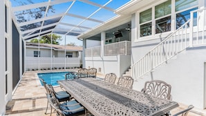Un espace extérieur abrité comprenant une piscine, une table à manger avec des chaises et un escalier menant à un deuxième étage.