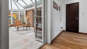 Quarto com uma grande porta de vidro deslizante que dá para um espaço de pátio externo, uma porta de madeira escura e uma parede de tijolos.