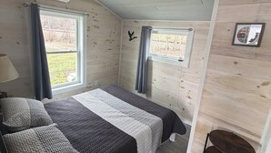A room with two beds, a window, a wall-mounted picture, and a small table.