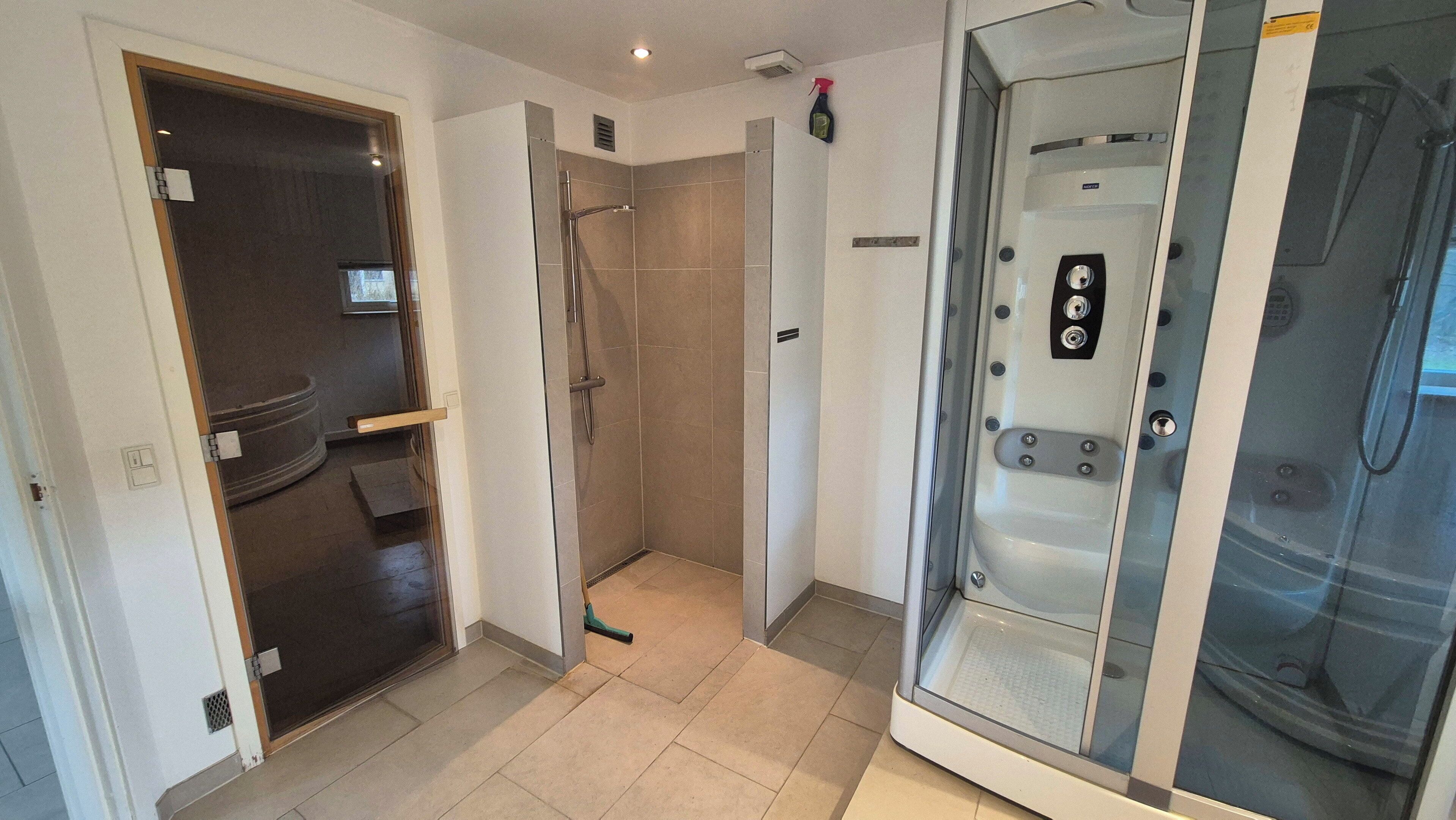 A bathroom with a shower, a toilet, and a glass-enclosed jacuzzi.