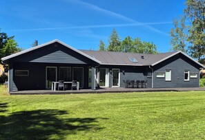 Een modern huis met twee verdiepingen, een overdekte veranda, grote ramen en een verzorgd gazon.