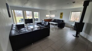 Una sala de estar moderna con un sofá de cuero negro, una mesa de comedor y un televisor.