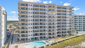 A multi-story hotel with balconies, a swimming pool, and a view of the beach. - The Enclave 503 | Beachfront | Zero Entry Pool | Tennis Courts | My Beach Getaways (Orange Beach)