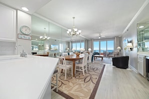 A modern kitchen with a large island, dining area with chairs, and a view of the ocean. - The Enclave 503 | Beachfront | Zero Entry Pool | Tennis Courts | My Beach Getaways (Orange Beach)