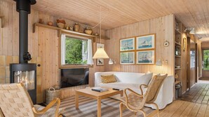 Ein Holzinterieur mit Kamin, weißem Sofa, Korbstühlen und einem Holztisch.