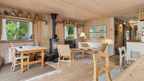 Ein Holzinterieur mit einem Tisch, Stühlen, einer Couch und einem Kamin.