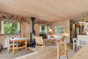 Un interior de madera con una mesa, sillas, un sofá y una chimenea.