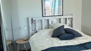 A bed with a white headboard, a bedside table, and a framed picture on the wall. - Coastal stay with great views (Redcliffe)
