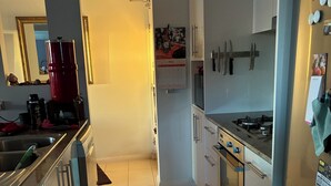 A modern kitchen with white cabinets, a gas stove, and a refrigerator. - Coastal stay with great views (Redcliffe)
