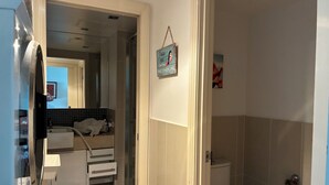 A bathroom with a toilet, a shower, and a sink. There is a towel rack and a small framed picture on the wall. - Coastal stay with great views (Redcliffe)