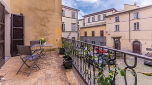 Un balcon avec une table et des chaises, des plantes en pot et une vue sur la rue.