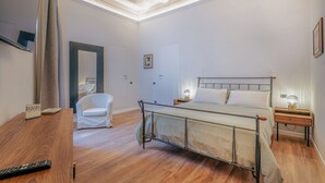 Une chambre à coucher comprenant un lit, des tables de chevet, une chaise, un bureau et un miroir.