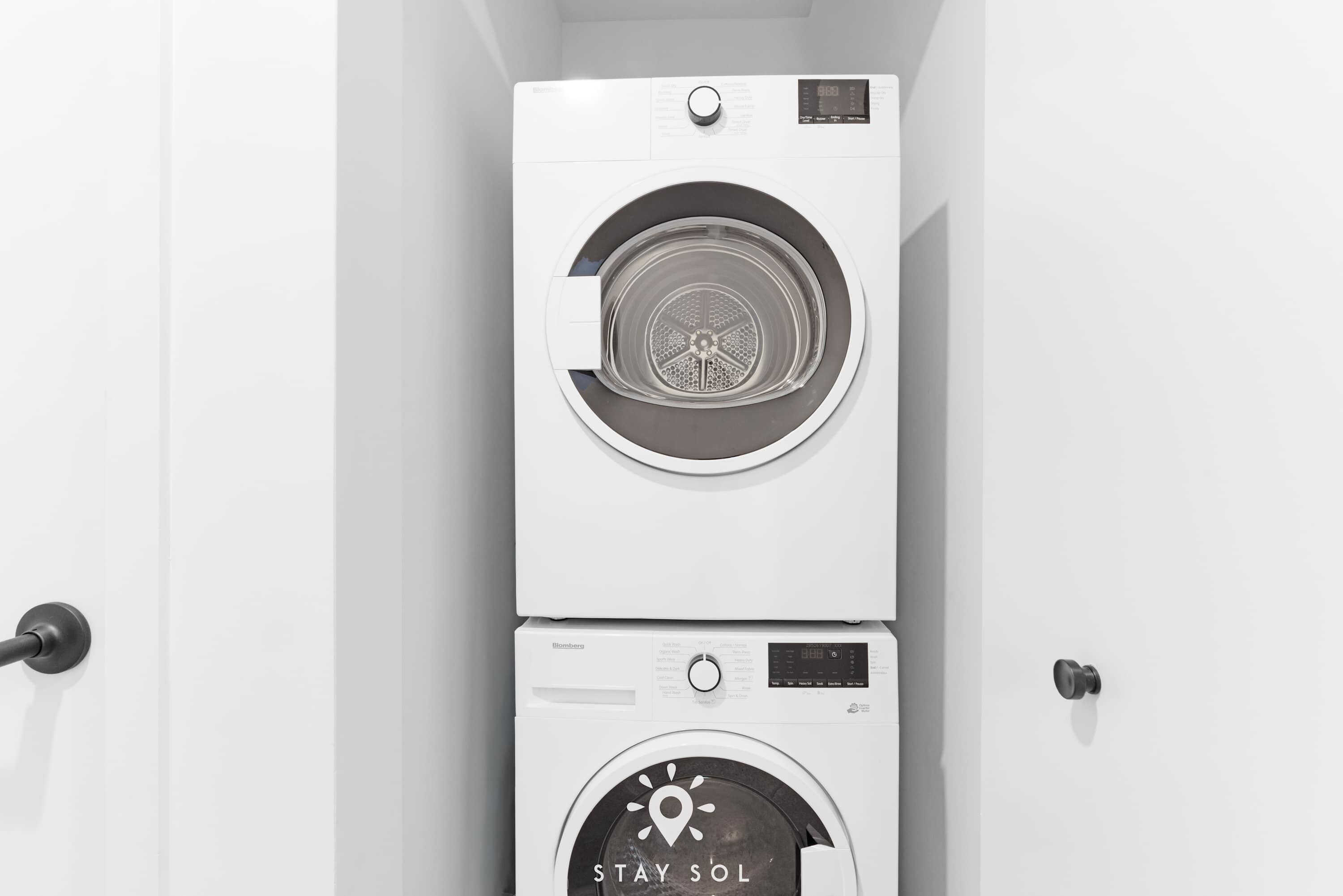 Two stacked white washing machines with a digital display and a 'STAY SOL' logo.