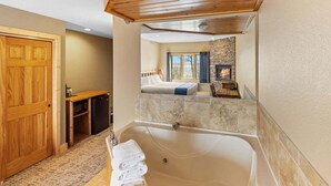 Ein Badezimmer mit einer großen Badewanne, einer Holztür und einer Steinwand.