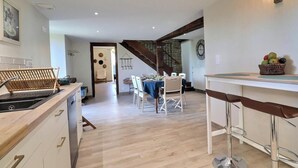 Eine moderne Küche mit Essbereich, Holzboden und einer Treppe, die zu einer weiteren Ebene führt.