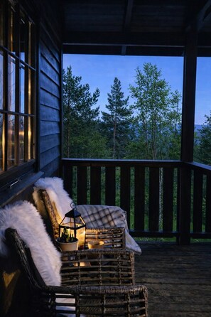 A wooden deck with a bench and a lantern, overlooking a forested area. - Secluded Cabin - Stunning Views - Hiking & Nature (Agder)