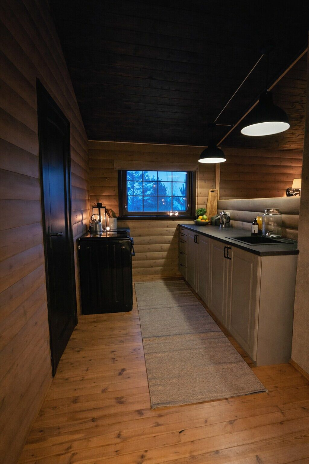 Ein rustikales Blockhaus-Interieur mit Küchenbereich, einem Fenster mit Blick und einer Deckenleuchte.