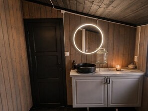 A kitchen with a wooden door, a countertop with a circular light fixture, and a cabinet. - Secluded Cabin - Stunning Views - Hiking & Nature (Agder)