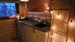 A cozy kitchen with wooden walls, a large island, pendant lights, and a view of the outdoors.