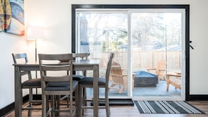 A room with a sliding glass door leading to a backyard, a dining table with chairs, a lamp, and a painting on the wall. - 5BR/3BA Stylish Modern Home in Decatur (Decatur)