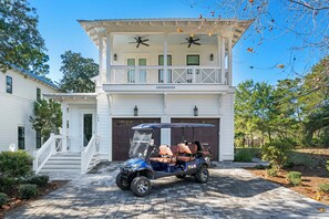 A two-story house with a covered porch, a golf cart parked in front, and a garage with a sign that reads "GOODHOVES". - Eastern Lake! Private Pool, LSV/Golf Cart, Bikes! Easy Walk to Beach! (Santa Rosa Beach)