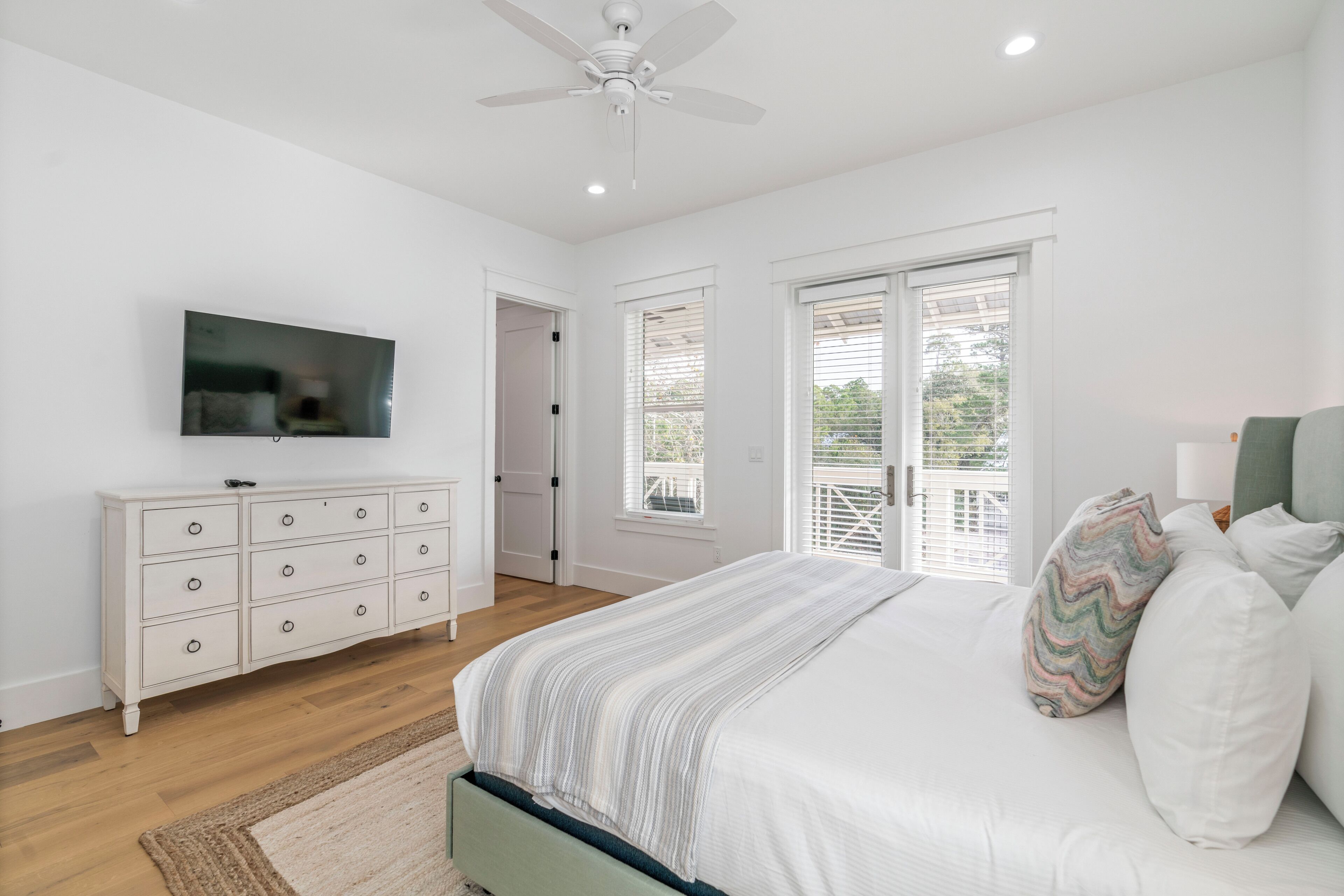 A bedroom with a bed, a dresser, a television, and a ceiling fan.
