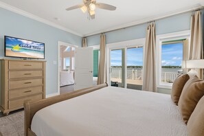 Een hotelkamer met een bed, een televisie, een dressoir en een balkon met uitzicht.