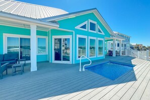 Een turquoise gebouw met een zwembad, terras en uitzicht op de oceaan.