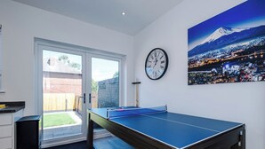 Et værelse med et ping-pong bord, et ur og et bybillede-maleri.