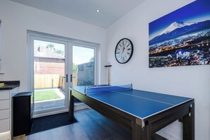 A room with a ping pong table, a clock, and a cityscape painting. - Modern Home for 9 with Garden (Greater Manchester)