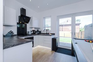 A modern kitchen with a built-in stove, microwave, and sink. - Modern Home for 9 with Garden (Greater Manchester)